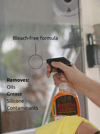 Man holding bottle of Crystal Clear, a detergent-free glass and multi-surface cleaner and degreaser that removes oils, silicone, and other contaminants.