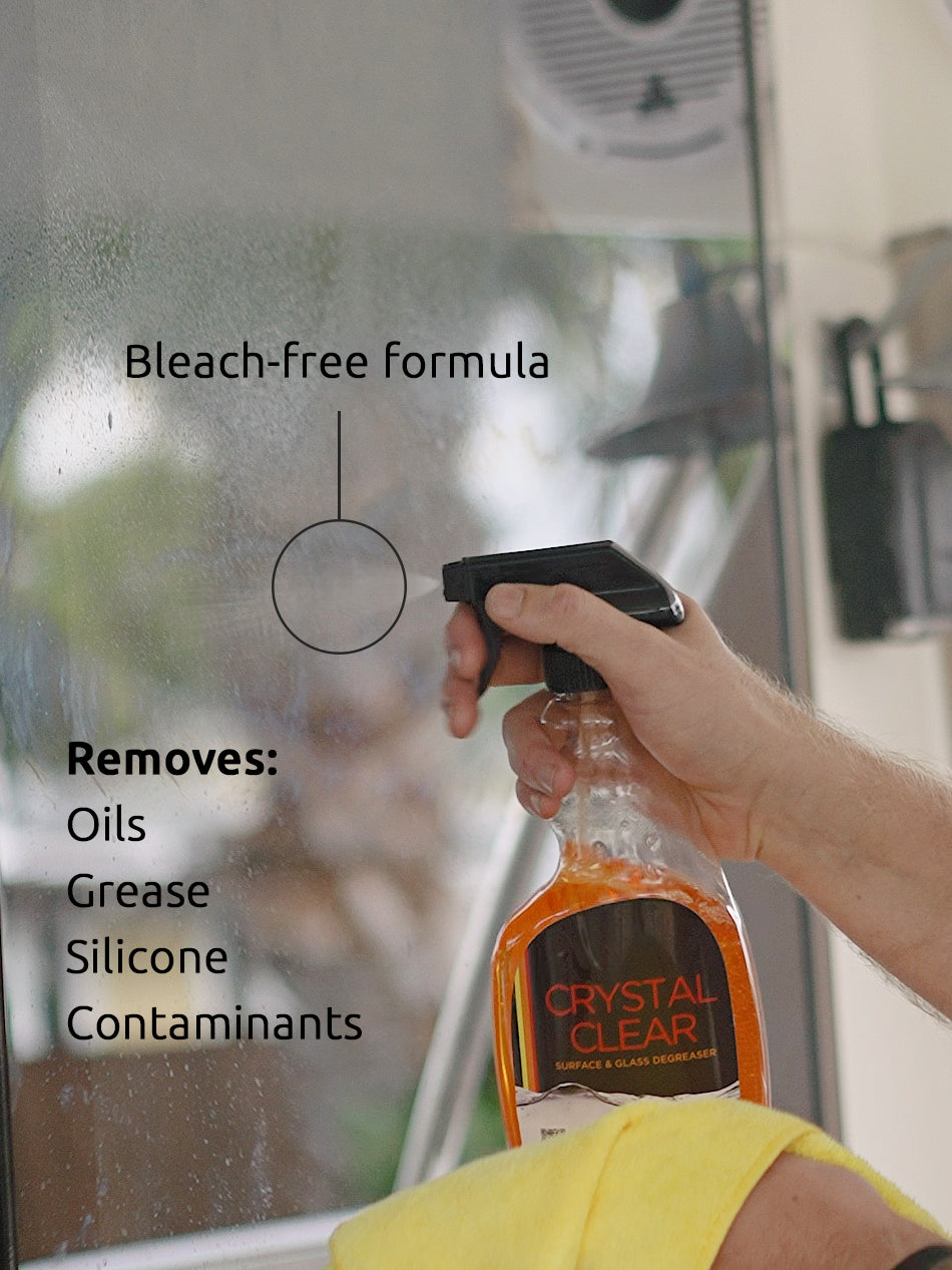 Man holding bottle of Crystal Clear, a detergent-free glass and multi-surface cleaner and degreaser that removes oils, silicone, and other contaminants.