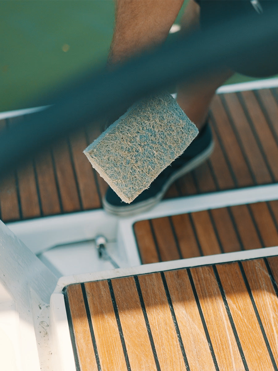 Man using doodle pad to clean teak deck with ditec's eco friendly teak cleaner, which effectively removes mold and mildew from teak and wood surfaces